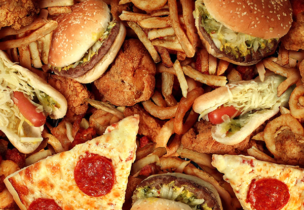 A pile of unhealthy fast food including pizza, burgers and French fries.